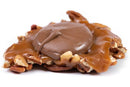 A Millican Pecan Milk Chocolate Caramillicans - Individual from Millican Pecan is displayed on a white background, revealing gooey caramel, crunchy pecans, and a layer of smooth milk chocolate on top.