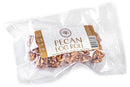A vacuum-sealed package contains a Millican Pecan Old-Fashioned Pecan Log Roll (5 oz), visible through the clear plastic. The label displays the Millican Pecan brand name, nutrition facts, and product details, highlighting this classic Southern candy made with premium Texas pecans.