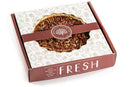 A boxed Millican Pecan Delicious Texas Southern Pecan Pie - 9 Inch with a clear window on top displaying the pie. The box features the word “FRESH,” illustrations of pecans, the American Pecan Pie logo, and proudly highlights the Millican Pecan brand.
