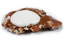 The Millican Pecan White Chocolate Caramillicans - Individual by Millican Pecan features a turtle-style candy with chopped pecans, a layer of caramel, and a dollop of white creamy topping, shown on a white background.
