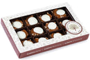 The Millican Pecan White Chocolate Caramillicans Gift Box by Millican Pecan features rich white chocolate pecan candy with pecans and creamy white chocolate on top, neatly arranged in twelve sections inside a white caramel pecan gift box with a clear lid.