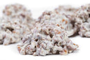 Close-up of Millican Pecan White Chocolate Pecan Cluster - Individually Wrapped candies, featuring clusters of pecans and pretzels coated in white chocolate from Millican Pecan. Each lumpy, textured gourmet cluster offers a delicious sweet and salty flavor combination, creating an irresistible individually wrapped treat against a white background.