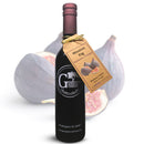 A bottle of Georgetown Olive Oil Co. Mission Fig Balsamic Vinegar with a gold tag, featuring images of figs. Crafted in Modena, Italy, this balsamic vinegar showcases the rich flavor of mission fig. The background displays whole and sliced figs, and the label reads “Georgetown Olive Oil Co.”.