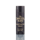 A black tube of Mustache Wax | The Immaculate Beard, 0.15 oz (4.25g), batch 1991, with white text on the label showcasing natural ingredients, stands upright on a reflective surface against a white background—ideal for sculpting a handlebar look with a neat finish.