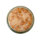 A glass jar of SALTOPIA Infused Sea Salts' Saltopia Garlic Salt: MOUTH FULL OF MAGIC, a coarse light brown garlic seasoning blend with visible sea salt crystals and dried orange-brown flakes, viewed from above on a white background.