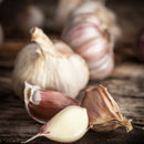 Close-up of whole garlic bulbs and cloves on rustic wood, ideal for infusing dishes with SALTOPIA Infused Sea Salts' Saltopia Garlic Salt: MOUTH FULL OF MAGIC—a gourmet blend of pure sea salt and fresh garlic with earthy, natural tones.