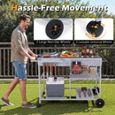 A man pushes the DirectDeals Movable Grill Table with 2 Spice Containers and Station for Backyard and BBQ on grass, holding food, drinks, utensils, and a cooler. Insets highlight its large non-slip and lockable universal wheels.