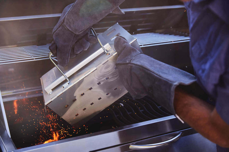 Napoleon PRO605CSS stainless steel charcoal cart grill with rear rotisserie burner and adjustable charcoal tray. Filling with charcoal. 