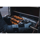 Wearing protective gloves, a person loads marinated meat onto the Napoleon Rotisserie Shish-Kebab Skewer Set (64008) by Napoleon Grills, preparing for hands-free kebab cooking outdoors.