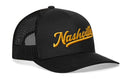 The Haka Hat Nashville Gold Script Trucker Hat is a black mesh snapback with "Nashville" embroidered in bold gold script, featuring the signature Haka Hat trucker style.