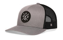 The Haka Hat New York City Trucker Hat features a gray-black design, mesh back, snapback closure, and a round front patch with intersecting lines, "NYC," and a central graphic.