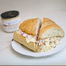 A large sandwich with creamy coleslaw sits on a plate, cut in four. In the background, Terrapin Ridge Farms Onion Blossom Horseradish Dip adds bold, zesty flavor as the perfect savory dipping sauce for your meal.