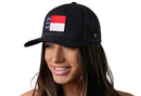 A woman smiles while wearing the Haka Hat North Carolina Flag Trucker Hat, a black NC snapback featuring a state flag patch, against a white background.