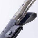 Close-up of the Messermeister Leather Belt Sheath for Overland Utility Knife, showing its snap closure, belt loop, and textured handle partially inserted into the premium leather sheath. The image highlights both Messermeister's detailing on handle and sheath.
