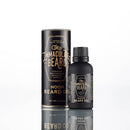 A bottle of Conditioning Natural Beard Oil by The Immaculate Beard is displayed in front of its matching cylindrical packaging, both featuring a sleek black design with gold text, set against a white background with a subtle reflection below. This high-quality beard oil also serves as an effective conditioner, helping to keep your facial hair soft and perfectly groomed.