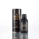 A bottle and cylindrical box of The Immaculate Beard Immaculate Fast Absorbing Beard Oil For Men Softens Skin, featuring black and gold labeling, stand on a reflective white surface to showcase this premium beard oil from The Immaculate Beard, specially formulated for fast absorption and ultimate beard conditioning.
