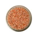 A glass jar of SALTOPIA Infused Sea Salts, featuring their Orange & Garlic Salt: ORANGE YOU TASTY, is photographed from above on a white background.