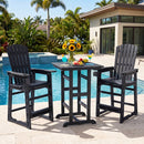 Two black DirectDeals Outdoor Bar Stool 29″ Height with Backrest and Armrests and a table set with drinks, fruit, and flowers sit poolside among tropical plants, framed by modern homes under a clear blue sky.