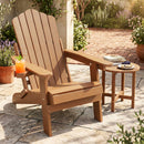 A DirectDeals Folding Adirondack Chair with Adjustable Backrest & Cup Holder sits on a stone patio with an orange drink, next to a small round table with pie and potted plants in the sunlight.