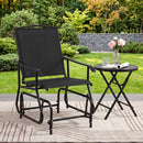 The DirectDeals Outdoor Glider Chair with Metal Frame and Armrests sits beside a small round table with a glass of water, a book, and pink flowers—ideal patio seating amid lush greenery.