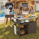 A man grills by the pool as three women dine nearby. Up front, the DirectDeals Outdoor Grill Cart with Storage Cabinet Shelves and Stainless Steel Top-Brown holds wine, bread, and pastries at this sunny get-together.