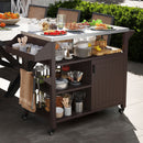 The DirectDeals Outdoor Grill Cart with Storage Cabinet Shelves and Stainless Steel Top-Brown holds jars, utensils, and dishes, topped with skewers, fruits, bowls, and cutting boards next to a dining table amid lush greenery.