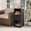 A DirectDeals Outdoor Storage Cabinet Patio Wicker Organizer with Drawer stands by a brown wicker sofa on a porch, holding bottles, cans, glasses, a drink dispenser, and a potted white-flowered plant nearby.