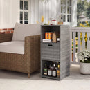 A DirectDeals Outdoor Storage Cabinet Patio Wicker Organizer with Drawer in gray stands by a brown wicker sofa, storing soda cans, glassware, a decanter, and liquor bottles. A potted plant rests on the porch railing nearby.