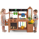 Two kids play at a DirectDeals Outdoor Wooden Mud Kitchen with Planter Box and Sink, using toy pans and cans. Chicks rest nearby while chalk art decorates the blackboard in their backyard play area.