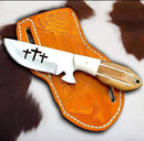 The Cowboy Bull Cutter Knife by Texan Knives features a handmade J2 steel blade with three cross cutouts, a polished wooden handle, and comes with a tooled leather sheath, all displayed on brown and white fur.
