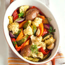 An oval dish of roasted vegetables—red potatoes, cauliflower, zucchini, carrots, bell peppers, onions, and garlic—garnished with fresh herbs and a sprinkle of SALTOPIA Lemon Pepper Salt: PUCKER UP BUSTER by SALTOPIA Infused Sea Salts.