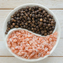 The SALTOPIA Infused Sea Salts Pink Himalayan & Gourmet Peppercorn Grinder Set features a white yin-yang dish with peppercorn medley and Pink Himalayan salt, set on light wood—an elegant addition to your spice collection.