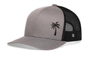 The Haka Hat Palm Tree Trucker Hat features a black embroidered palm tree on a gray front panel, a black mesh back, and a small black H logo on the side. This stylish snapback is part of the Haka Hat collection.