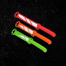 Three Messermeister Petite Messer Parer Trio Set knives with matching sheaths in red, orange, and green are arranged diagonally on a black textured surface, showcasing the brand’s vibrant design.