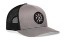 The Haka Hat Phoenix Trucker Hat | Gray-Black PHX X Snapback features a gray and black design, round patch with P, H, X letters and trident symbol, black mesh back, and showcases the signature Haka Hat 5.0 style.