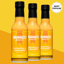 Three bottles of Bravado Spice Pineapple & Habanero Hot Sauce from Bravado Spice are arranged against a yellow background, featuring a “Most Popular” badge in the top right corner. The labels highlight this tropical sauce as having medium heat.