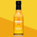 A bottle of Bravado Spice Co Pineapple & Habanero Hot Sauce—a lively fruit-forward condiment featuring a yellow label, black cap, and the Medium heat level indicated—displayed on a yellow background.