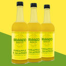 Three bottles of Bravado Spice Co Pineapple & Jalapeño Margarita Mixer are arranged side by side on a green and yellow background. Their vibrant yellow labels showcase bold text and product details, making them an ideal craft margarita mixer for cocktail enthusiasts.