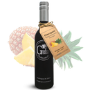 A bottle of Georgetown Olive Oil Co. Pineapple White Balsamic from Georgetown Olive Oil Co., featuring a tag with a pineapple image, is displayed in front of a whole pineapple and a pineapple slice on a white background.
