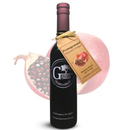 A bottle of Georgetown Olive Oil Co. Pomegranate Balsamic Vinegar by Georgetown Olive Oil Co., featuring a tag, is displayed in front of a halved pomegranate with vibrant seeds.
