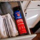 A can of Prepared Hero Fire Spray by Prepared Hero, essential for kitchen fire safety, sits in a partially open drawer next to folded dish towels beneath a granite countertop.