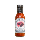 A bottle of Brushfire Farms Prickly Pear BBQ Sauce, distinguished by its white label adorned with a vivid cactus and flames illustration, embodies the bold essence of Texas in every flavorful drop.
