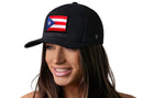 A woman with long brown hair smiles and looks to the side, wearing the Haka Hat Puerto Rico Flag Trucker Hat (Black PR Snapback) by Haka Hat against a plain white background.