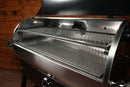 A stainless steel pellet grill equipped with the Pimp My Grill® Gen2 Slide-Out Rack System, featuring two stacked, metal wire racks inside the open cook chamber.