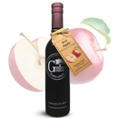 A bottle of Georgetown Olive Oil Co. Red Apple Balsamic Vinegar by Georgetown Olive Oil Co., artfully aged in Modena, Italy, is displayed with a tag in front of a whole apple and an apple slice—each showing a visible leaf and seeds.