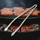Butcher BBQ Rotating Barbecue Tongs are held over a grill filled with hot coals and sizzling hot dogs, as smoke rises from the barbecue.
