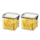 Two square, clear plastic containers from Lovely Home Icon—part of the 1-4PCS Sealed Jars Kitchen Organizer Grain Storage Boxes set—are filled with yellow cornflakes, each featuring a black latch on the lid. Placed side by side on a white background, these large-capacity sealed containers offer a practical and eco-friendly solution for keeping your food fresh and organized.