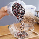 A hand pours a colorful assortment of beans and grains from the Lovely Home Icon Plastic Sealed Tank Large Capacity Crisper—a clear, airtight kitchen storage box with measurement scale—into a glass bowl on a wooden table.