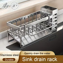 A Lovely Home Icon Sink Cleaning Tools Storage Rack rests on the kitchen counter, acting as a multifunctional organizer for sponges, cleansers, and rags. Crafted from stainless steel for durability, this rack features a dedicated utensil hanger and an integrated tray beneath for efficient water drainage. Text labels emphasize its robust construction and quick-drain functionality.