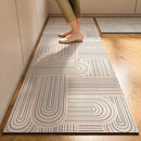 A person wearing beige pants and shoes stands on the Lovely Home Icon New 1 pc Japanese style soft kitchen diatomite mud floor mat, which features a modern geometric design with curved and straight lines. This super anti-slip, super absorbent rug offers stability and comfort on the room’s wooden floors, making it easy to handle for everyday living.